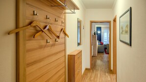 A hallway with wooden paneling, a wooden dresser, and a coat rack. - Comfort plus apartment with 1 bedroom and balcony on the upper floor (Ostseebad Binz)