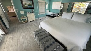 A bedroom with a large bed, a bedside table, a dresser, a mirror, and a window with blinds. - KINGSLEY LAKE! Spring fed, best lake in Fl, great fishing, waterskiing… (Starke)