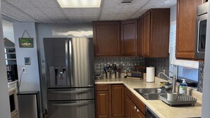 A modern kitchen with stainless steel appliances, wooden cabinets, and a tiled backsplash. - KINGSLEY LAKE! Spring fed, best lake in Fl, great fishing, waterskiing… (Starke)