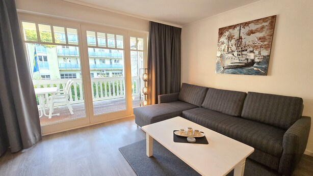 Ein modernes Wohnzimmer mit einem grauen Sofa, einem weißen Couchtisch und einem Gemälde eines Schiffes an der Wand.