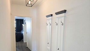 Ein Flur mit Holzboden, einer Tür zu einem Zimmer und einer Fußmatte am Eingang.
