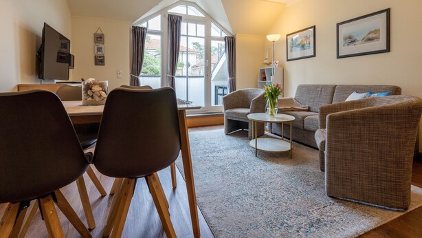 En moderne stue med spiseplads, en sofasæt, et sofabord og et fjernsyn.