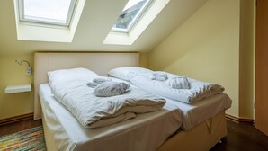 Et soveværelse med to senge, ovenlys, en lille hylde og et farverigt tæppe.