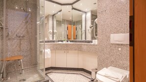 Un bagno moderno con doccia vetrata, un water e un angolo lavabo.