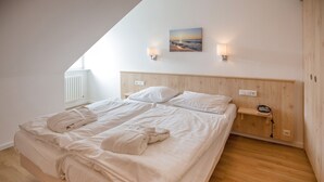 Una camera da letto con una testiera in legno, un letto con lenzuola bianche, un comodino con una lampada e un quadro appeso al muro.