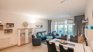 Ein modernes Wohnzimmer mit Essbereich, Kamin und großen Fenstern.