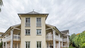 Ein zweistöckiges Gebäude mit einer symmetrischen Fassade, mehreren Balkonen und einem flachen Dach.