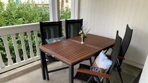 A wooden table with chairs on a covered patio. - Comfort apartment with 1 bedroom and balcony on the upper floor (Ostseebad Binz)