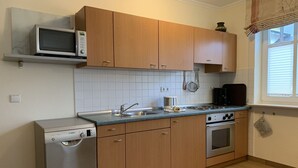 A kitchen with wooden cabinets, a stainless steel dishwasher, a microwave, a stove, and a coffee maker. - Comfort apartment with 1 bedroom and balcony on the upper floor (Ostseebad Binz)