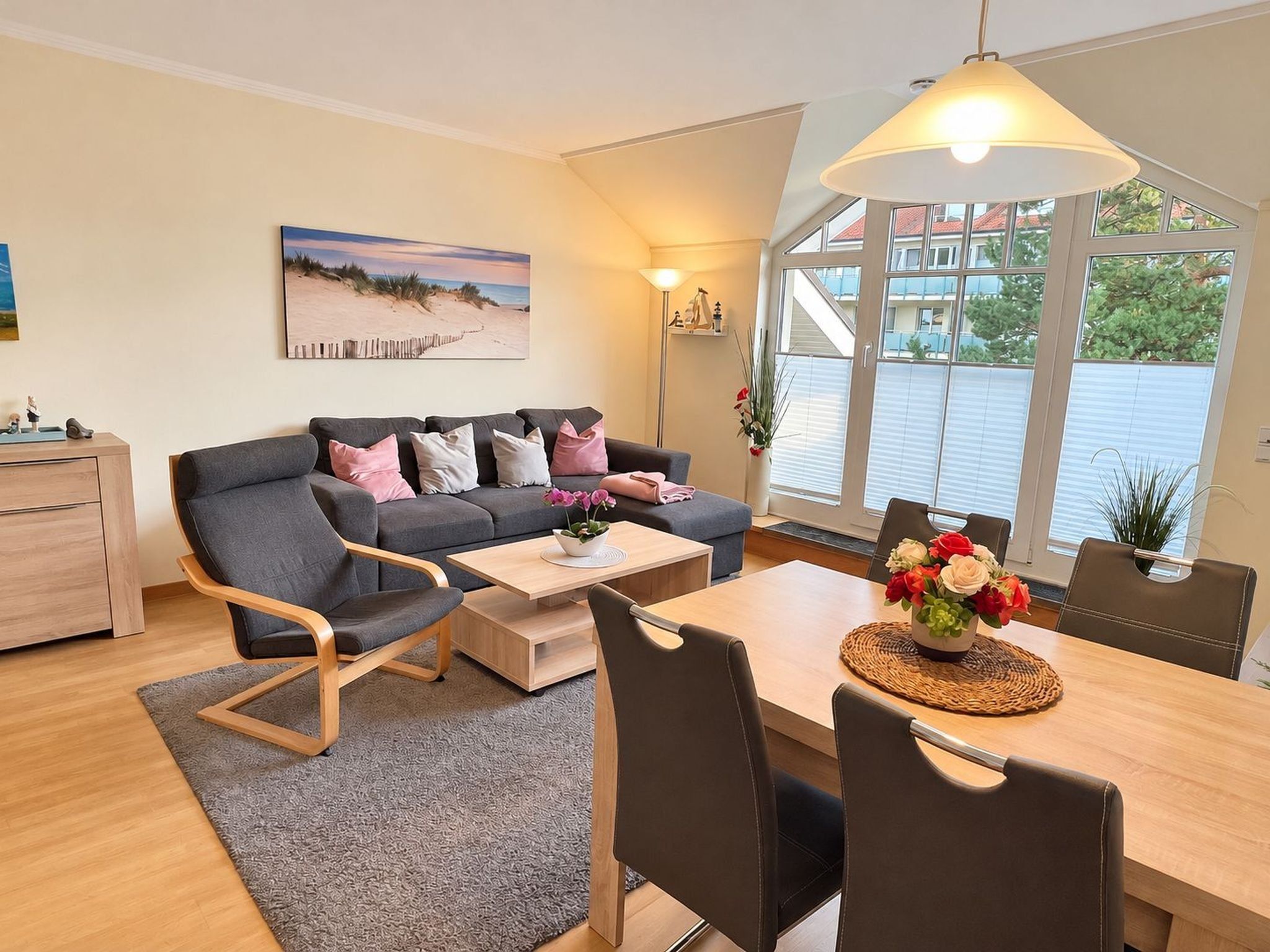 Un salon moderne comprenant un canapé, une table basse, une table à manger, des chaises et une grande fenêtre donnant sur un beau paysage.