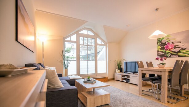 Un salon moderne comprenant un canapé, une table basse, un téléviseur, une table à manger et des chaises.