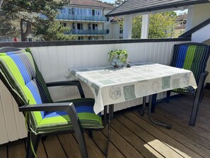 A wooden deck with a table and chairs, a potted plant, and a view of a residential building. - Comfort plus apartment with 1 bedroom and balcony on the top floor (Ostseebad Binz)
