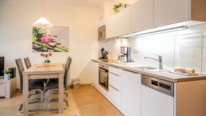 Une cuisine moderne avec des meubles blancs, un four encastré, une machine à café et un évier.