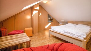 Una piccola camera da letto moderna con soffitto spiovente, arredamento in legno e un letto con biancheria bianca.