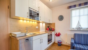 Una cucina moderna con mobili bianchi, elettrodomestici in acciaio inossidabile e un piano di lavoro in legno.