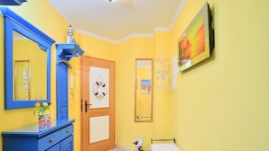 Een kamer met een blauwe kast, een bed, een deur met een decoratie van een reddingsboei en een aan de muur hangend schilderij.