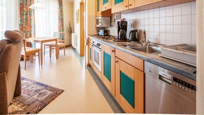 Ett modernt kök med träskåp, en diskmaskin från Siemens och en matplats med bord och stolar.