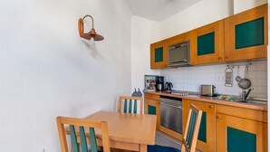 Eine kleine Küche mit Holzschränken, einem eingebauten Ofen und einer Essecke mit zwei Stühlen und einem Tisch.