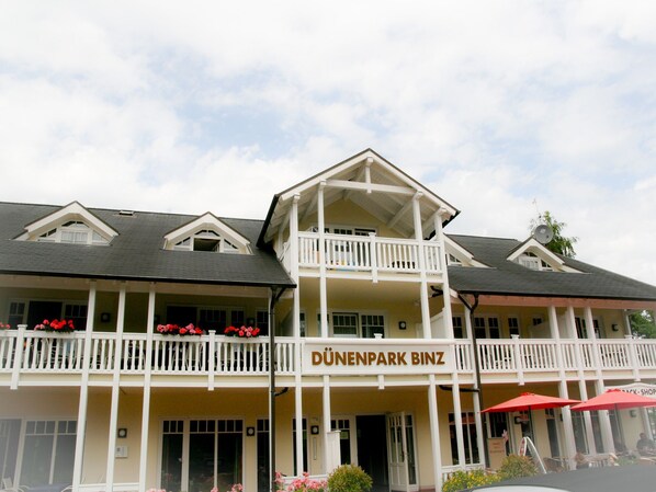 Um edifício de dois andares com uma varanda e uma placa com a inscrição 'DÜNENPARK BINZ'.