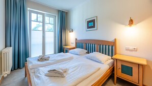 Ein Hotelzimmer mit einem Bett, einem Nachttisch, Vorhängen an einem Fenster, einer Heizung und einer Wandleuchte.