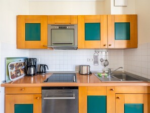 A kitchen with wooden cabinets, a built-in oven, a dishwasher, a sink, and a coffee maker.