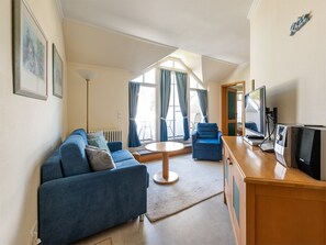 A modern living room with a blue sofa, a round coffee table, and a TV on a wooden stand.