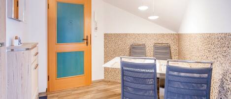 A dining area with a wooden floor, a table with two chairs, and a ceiling light fixture.