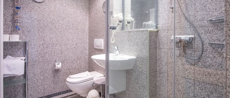 Um banheiro moderno com pia de bancada em granito, vaso sanitário e chuveiro com box de vidro.