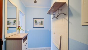 Een badkamer met een houten wastafelmeubel, een spiegel, een lijstwerk schilderij en een plafondlamp.