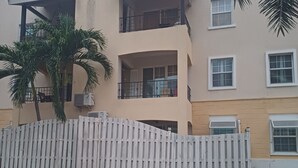 A multi-story residential building with balconies, a white picket fence, and a palm tree. -  Enchanted at winchester kick back and relax at this modern stylish apartment  
 (Kingston)