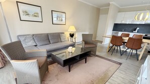 Een moderne woonkamer met een bank, stoelen, een salontafel en een eethoek met stoelen en een tafel.
