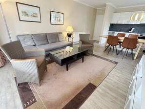 Ein modernes Wohnzimmer mit einer Couch, Sesseln, einem Couchtisch und einem Essbereich mit Stühlen und einem Tisch.