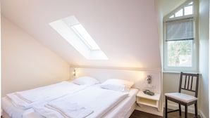 Een slaapkamer met dakraam, een bed, een stoel en een nachtkastje.
