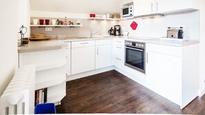 Een moderne keuken met witte kastjes, een ingebouwde oven, een magnetron en een broodrooster.