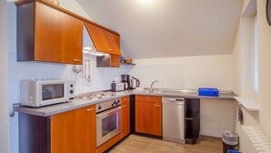 A compact kitchen with wooden cabinets, a microwave, an oven, a dishwasher, and a sink. - Comfort apartment with 2 bedrooms and balcony on the top floor (Ostseebad Binz)
