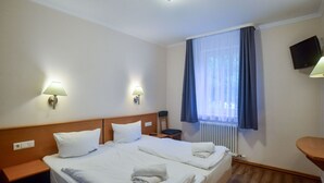 A hotel room with two beds, bedside lamps, a TV, and a window with curtains. - Komfort Ferienwohnung mit 1 Schlafzimmer und Terrasse im Erdgeschoss (Ostseebad Binz)