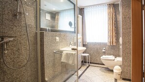 A modern bathroom with a glass-enclosed shower, a sink, and a toilet. - Comfort apartment with 1 bedroom and balcony on the upper floor (Ostseebad Binz)