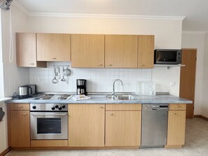 Eine moderne Küche mit Holzschränken, Edelstahlgeräten und einem eingebauten Geschirrspüler.