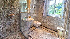Une salle de bain moderne avec une douche à parois de verre, un lavabo blanc et des toilettes.