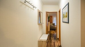 A narrow hallway with wooden flooring, a bench, a coat rack, and a framed picture on the wall. - Comfortplus vacation apartment with 1 bedroom and terrace on the first floor (Ostseebad Binz)