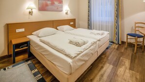 A hotel room with a double bed, bedside lamps, a small table, a chair, and a painting on the wall. - Comfortplus vacation apartment with 1 bedroom and terrace on the first floor (Ostseebad Binz)