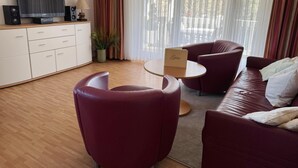 Een moderne woonkamer met een bank, fauteuils, een salontafel, een televisie en een kast.