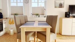 Een moderne keuken met een eettafel, stoelen, een klok en een schilderij van een trein aan de muur.