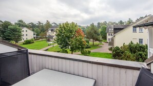 A balcony with a table and chairs, overlooking a residential area with houses and a tree. - Comfort apartment with 1 bedroom, balcony and bedroom on the top floor (Ostseebad Binz)