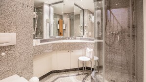 A modern bathroom with a granite countertop, a glass-enclosed shower, and a large mirror above the sink. - Comfort apartment with 1 bedroom, balcony and bedroom on the top floor (Ostseebad Binz)