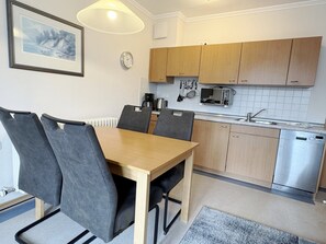 A compact kitchen with wooden cabinets, a built-in microwave, and a coffee maker. - Comfort Apartment with 1 bedroom, a balcony, and a bedroom on the top floor (Ostseebad Binz)