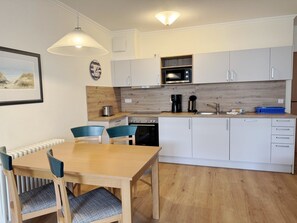 A modern kitchen with white cabinets, a wooden countertop, a Bosch oven, and a coffee maker.