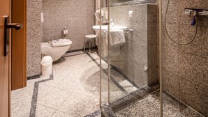 Un baño moderno con ducha de mampara de vidrio, inodoro y lavamanos.