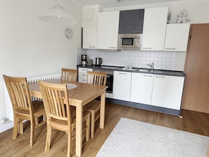 A compact kitchen with white cabinets, a microwave, a coffee maker, and a sink. - Komfortplus Vacation Apartment with 1 bedroom and a balcony on the top floor (Ostseebad Binz)