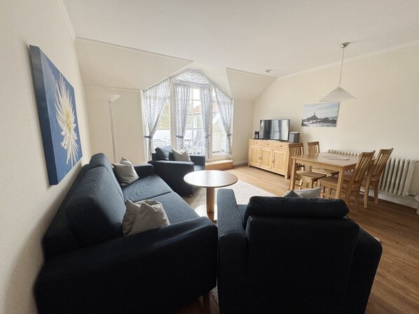 A modern living room with a sofa, a round coffee table, and a dining area with a table and chairs.